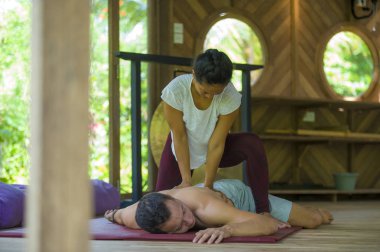 Genç, güzel ve egzotik Asyalı Endonezyalı kadın erkek için geleneksel Tayland masajı yapıyor. Tropikal sağlıklı yaşam tarzında rahatlamış.