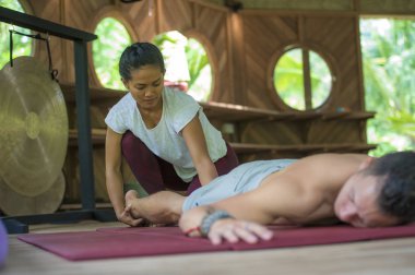 Genç, güzel ve egzotik Asyalı Endonezyalı kadın erkek için geleneksel Tayland masajı yapıyor. Tropikal sağlıklı yaşam tarzında rahatlamış.