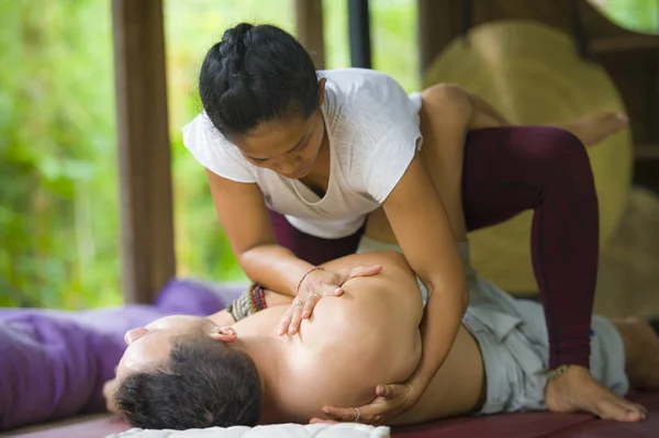 Joven hermosa y exótica mujer terapeuta indonesia asiática dando masaje tailandés tradicional al hombre relajado en el spa tropical de bienestar en estilo de vida natural saludable —  Fotos de Stock