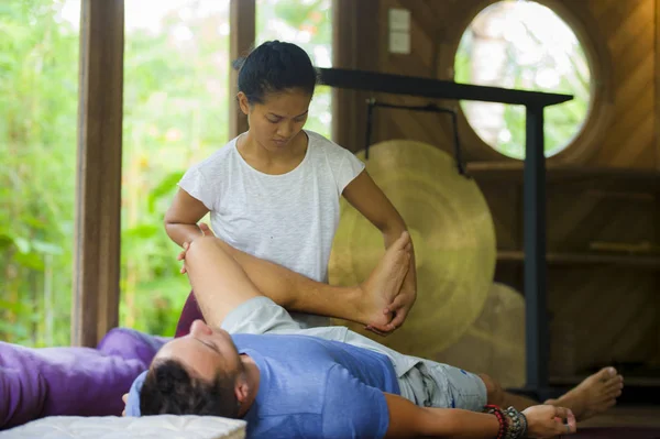young beautiful and exotic Asian Indonesian therapist woman giving traditional Thai massage to man relaxed at tropical wellness spa in healthy natural lifestyle