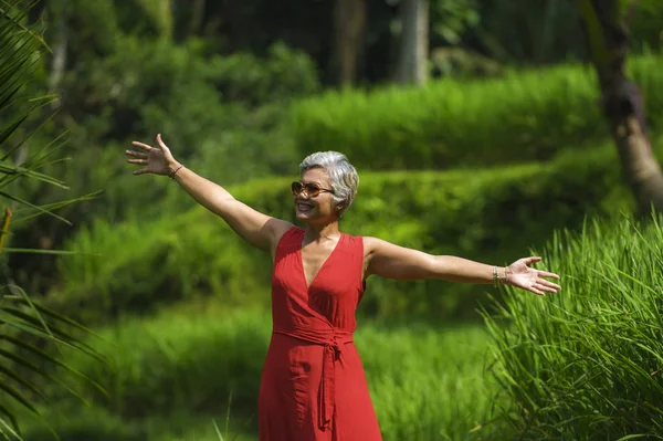 Estilo de vida natural retrato de bela e feliz idade média 40 ou 50 anos Mulher asiática com cabelos grisalhos em vestido vermelho elegante andando na paisagem verde floresta tropical — Fotografia de Stock