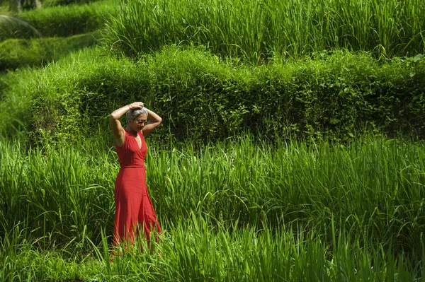 Přirozený životní styl portrét krásného a šťastného středního věku 40s nebo 50 000 žen s šedými vlasy ve stylových červených šatech po zelené tropické lesní krajině — Stock fotografie