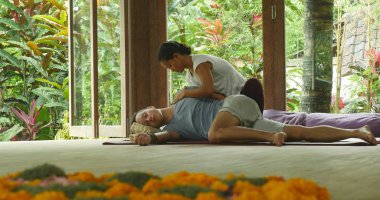 Genç, güzel ve egzotik Asyalı Endonezyalı kadın erkek için geleneksel Tayland masajı yapıyor. Tropikal sağlıklı yaşam tarzında rahatlamış.