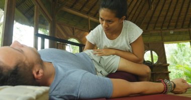 Genç, güzel ve egzotik Asyalı Endonezyalı kadın erkek için geleneksel Tayland masajı yapıyor. Tropikal sağlıklı yaşam tarzında rahatlamış.