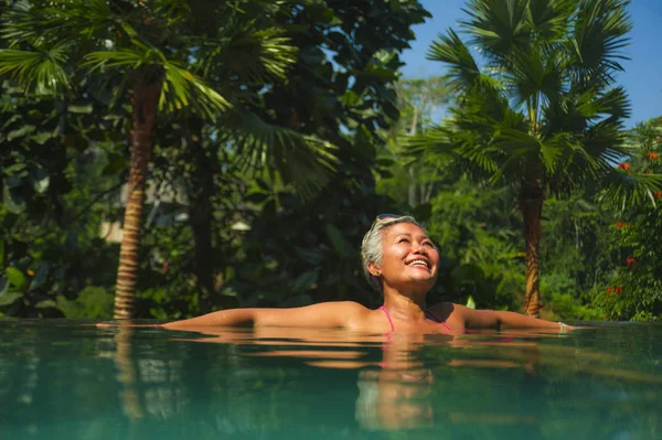 Lifestyle-Porträt attraktiver und glücklicher Asiatinnen mittleren Alters entspannt im tropischen Resort Infinity-Pool mit Dschungel-Hintergrund entspannt genießen — Stockfoto