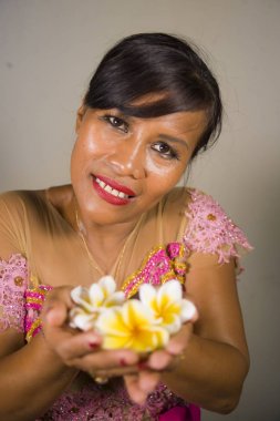 güzel ve mutlu orta yaşlı Endonezya Bali kadın geleneksel tören elbise gülümseyerek ve Bali Hindu dinine hoş geldiniz elinde çiçek sunan tutarak