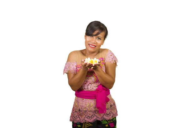 Szép és boldog középkorú indonéz balinéz nő a hagyományos szertartás ruhát mosolyogva és gazdaság virág kínál a kezében, szívesen Bali hindu vallás — Stock Fotó