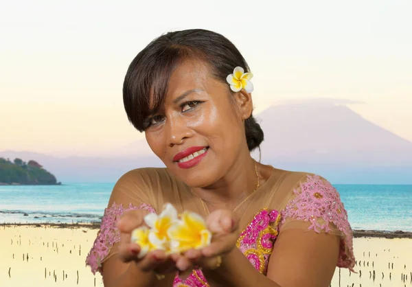 Красиві щасливі середнього віку Індонезійська балійскій жінка в традиційному одязі церемонія в тропічному пляжі з Балі Agung вулкана тлі у відпустку туристичний напрямок — стокове фото