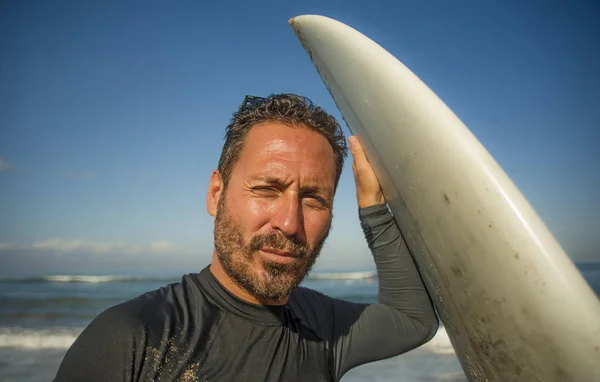 Stilig och attraktiv surfare man i neopren baddräkt innehav surfbräda poserar cool efter surfing njuta av sommarvatten sport och semester — Stockfoto