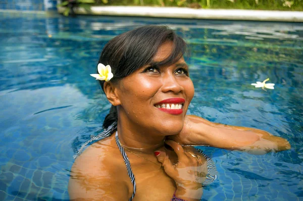 Outdoors lifestyle portrait of middle aged 40s or 50s attractive and happy Asian Indonesian woman in biking enjoying holidays at Bali villa or tropical resort swimming pool — Stock Photo, Image