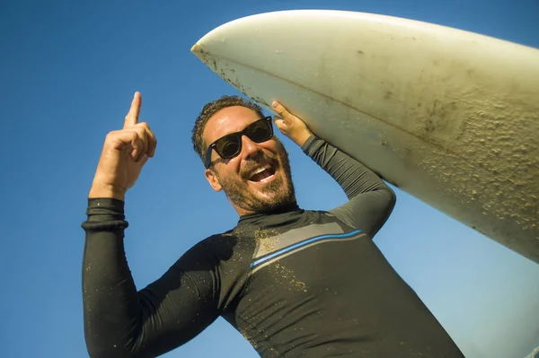 Livsstil porträtt av attraktiva och Happy Surfer man 3os till 40s i neopren surfing baddräkt poserar med surfbräda på stranden njuter vattensport och sommarlov — Stockfoto