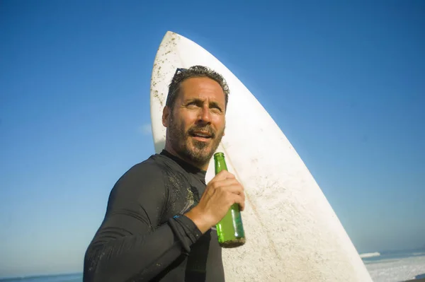 Livsstil porträtt av attraktiva och Happy Surfer man 3os till 40s i neopren surfing baddräkt poserar med surfbräda på stranden njuter vattensport och sommarlov — Stockfoto