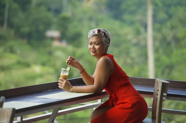 Estilo de vida natural al aire libre retrato de mujer indonesia asiática atractiva y feliz de mediana edad en vestido rojo con estilo disfrutando de viaje de vacaciones tropicales en el complejo turístico — Foto de Stock