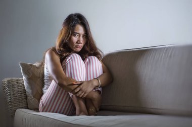 Genç üzgün ve bunalımlı Endonezyalı kadın, evde oturmuş, üzüntülü ve üzgün bir şekilde ağlıyordu.