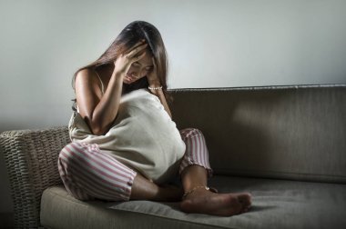 Genç üzgün ve bunalımlı Endonezyalı kadın. Kanepesinde ağlayan, hayal kırıklığına uğramış ve üzüntülü bir şekilde ayrılık sonrası depresyona girmiş.