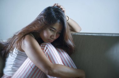 Genç üzgün ve bunalımlı Endonezyalı kadın, evde oturmuş, üzüntülü ve üzgün bir şekilde ağlıyordu.