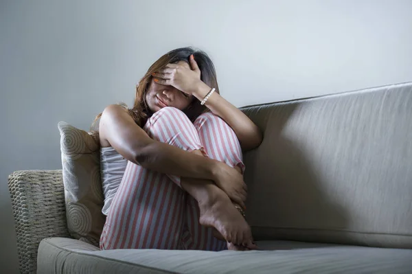 Молодая грустная и подавленная азиатская индонезийская женщина сидит дома на диване и плачет расстроенный и расстроенный страдание стресс и депрессия после разрыва — стоковое фото