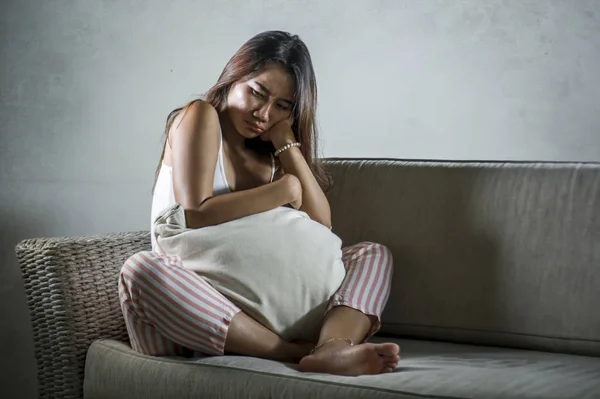 Nuori surullinen ja masentunut aasialainen indonesialainen nainen pistely kotona sohvalla itku turhautunut ja järkyttynyt kärsimystä stressiä ja masennusta hajoamisen jälkeen — kuvapankkivalokuva