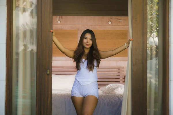 Joven atractivo y sexy asiático indonesia mujer en pijama despertar de cama en la mañana apertura balcón ventana sonriendo relajado disfrutar de vacaciones — Foto de Stock