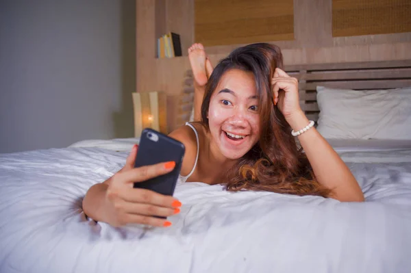 Jeune adolescente attrayante et heureuse couchée détendue et souriante gaie au lit en utilisant les médias sociaux Internet ou en ligne sortir ensemble app avec téléphone mobile à la maison — Photo