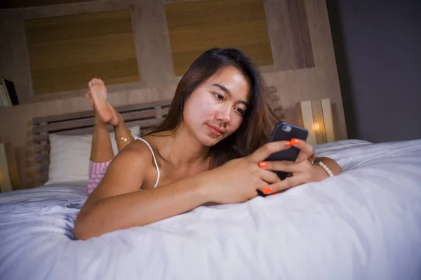 Jong aantrekkelijk en gelukkig tiener vrouw liggend ontspannen en lachend vrolijk in bed met behulp van internet social media of online dating app met mobiele telefoon thuis — Stockfoto