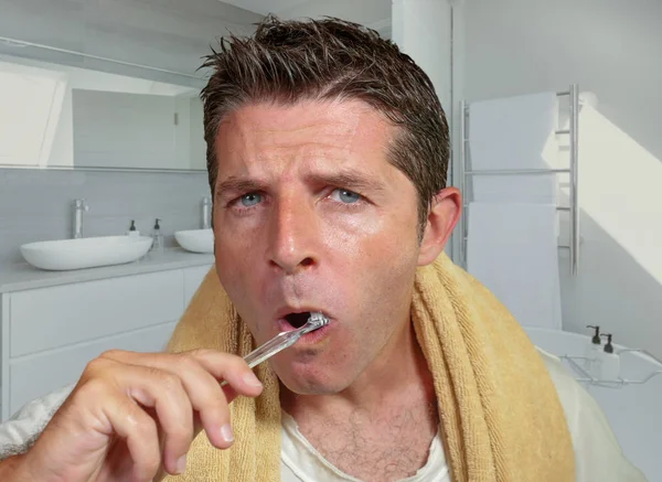 Estilo de vida natural retrato de joven atractivo y feliz hombre caucásico en el baño de casa lavándose el diente con cepillo de dientes mirando en el espejo en el cuidado dental — Foto de Stock