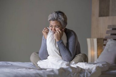 yatakta gri saçlı çekici üzgün ve depresif orta yaşlı kadının dramatik yaşam tarzı ev portresi depresyon ve anksiyete acı üzgün duygu