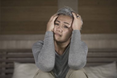 çekici üzgün ve gri saçlı kayıp orta yaşlı kadının dramatik yaşam tarzı ev portresi sinirli depresyon ve ağrı acı duygu yatakta oturan