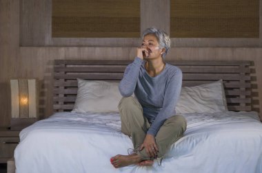 çekici üzgün ve gri saçlı kayıp orta yaşlı kadının dramatik yaşam tarzı ev portresi sinirli depresyon ve ağrı acı duygu yatakta oturan