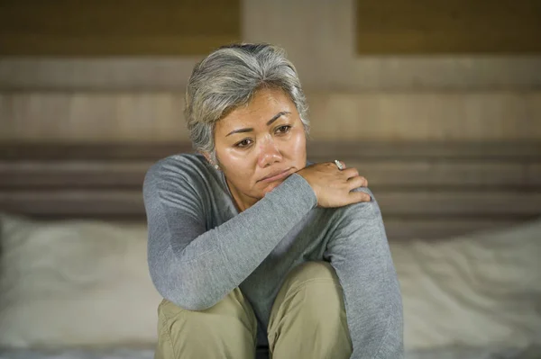 Dramatisches Lebensstil-Porträt einer attraktiven, traurigen und depressiven Frau mittleren Alters mit grauen Haaren auf dem Bett, die unter Depressionen und Angstzuständen leidet — Stockfoto