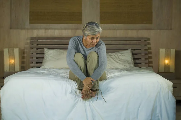 Deprimida y triste pelo gris mujer madura llorando sola sentada en la cama sufriendo crisis de dolor y depresión problema sintiéndose perdida y abrumada en casa — Foto de Stock