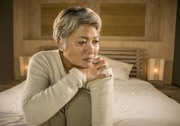 Deprimida y triste pelo gris mujer madura llorando sola sentada en la cama sufriendo crisis de dolor y depresión problema sintiéndose perdida y abrumada en casa —  Fotos de Stock