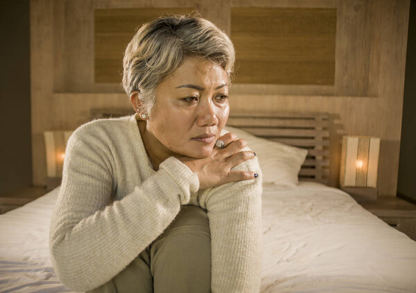 depressed and sad grey hair mature woman crying lonely sitting on bed suffering crisis in pain and depression problem feeling lost and overwhelmed at home
