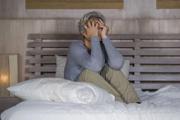 Dramatisches Lebensstil-Porträt einer attraktiven, traurigen und depressiven Frau mittleren Alters mit grauen Haaren auf dem Bett, die unter Depressionen und Angstzuständen leidet — Stockfoto