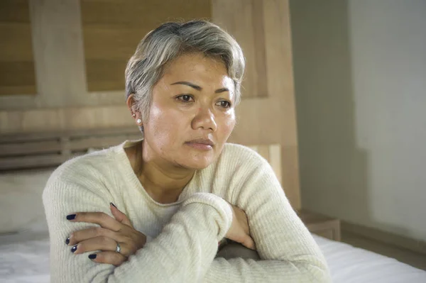 Deprimida y triste pelo gris mujer madura llorando sola sentada en la cama sufriendo crisis de dolor y depresión problema sintiéndose perdida y abrumada en casa —  Fotos de Stock