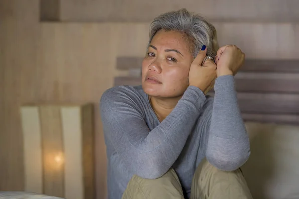 Dramatisches Lebensstil-Porträt einer attraktiven, traurigen und depressiven Frau mittleren Alters mit grauen Haaren auf dem Bett, die unter Depressionen und Angstzuständen leidet — Stockfoto