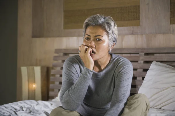 Mode de vie dramatique portrait à la maison d'attrayant triste et perdu femme d'âge moyen avec les cheveux gris assis sur le lit sentiment frustré souffrant de dépression et de douleur — Photo