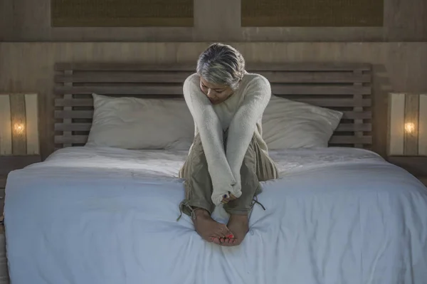 Δραματική ζωή σπίτι πορτρέτο της ελκυστική λυπημένη και χαμένη μεσήλικες γυναίκα με γκρίζα μαλλιά κάθονται στο κρεβάτι νιώθοντας απογοητευμένοι υποφέρουν κατάθλιψη και τον πόνο — Φωτογραφία Αρχείου