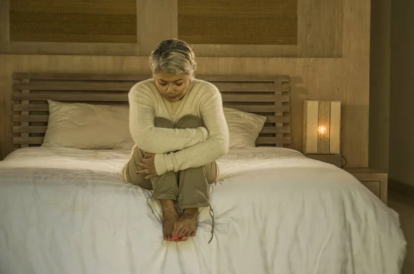Dramatic lifestyle home portrait of attractive sad and lost middle aged woman with grey hair sitting on bed feeling frustrated suffering depression and pain — Stock Photo, Image