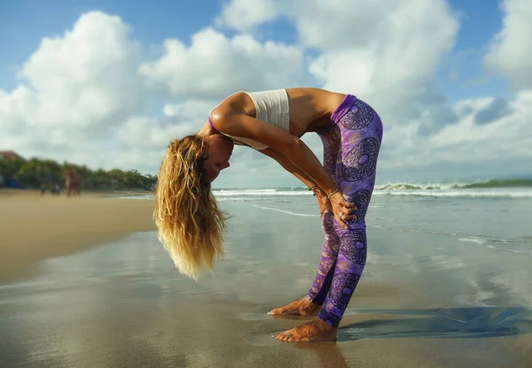 Joven mujer rubia feliz y atractiva en forma y delgada haciendo yoga y ejercicio de relajación al aire libre en la hermosa playa en la práctica de relajación y meditación — Foto de Stock