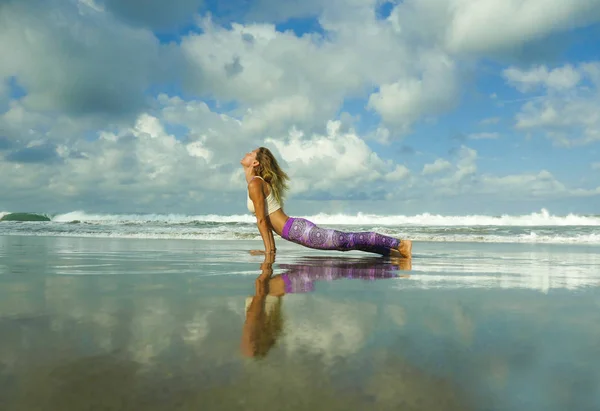 Young happy and attractive fit and skinny blond woman doing yoga and relaxation exercise outdoors at beautiful beach in relax and meditation practice — Zdjęcie stockowe