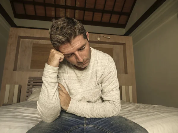 Dramatický domácí portrét 30 až 40s atraktivního a zoufalého muže sedícího na posteli trpící úzkostí a depresí, plačící smutný a zamyšlený — Stock fotografie