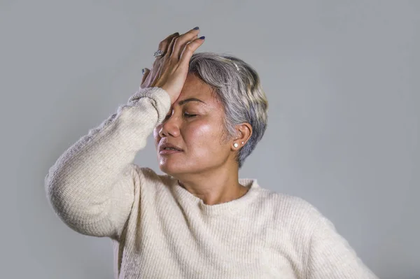 Драматический портрет привлекательной грустной и депрессивной азиатки средних лет, плачущей беспомощной страдающей депрессией и тревожным кризисом боли и отчаянного лица — стоковое фото