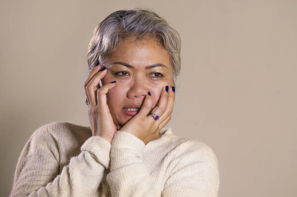dramatic portrait of attractive sad and depressed middle aged Asian woman crying helpless suffering depression problem and anxiety crisis in pain and desperate face