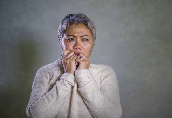 Dramatisches Porträt einer attraktiven, traurigen und depressiven asiatischen Frau mittleren Alters, die hilflos weint und unter Depressionen leidet. — Stockfoto