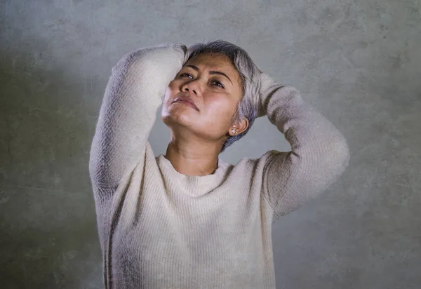 Dramatisches Porträt einer attraktiven, traurigen und depressiven asiatischen Frau mittleren Alters, die hilflos weint und unter Depressionen leidet. — Stockfoto