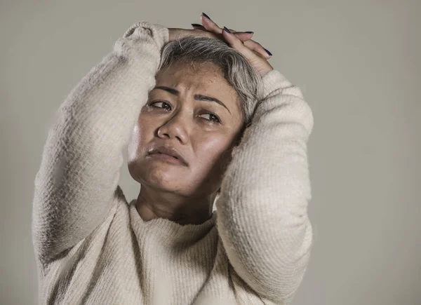 Dramatisches Porträt einer attraktiven, traurigen und depressiven asiatischen Frau mittleren Alters, die hilflos weint und unter Depressionen leidet. — Stockfoto