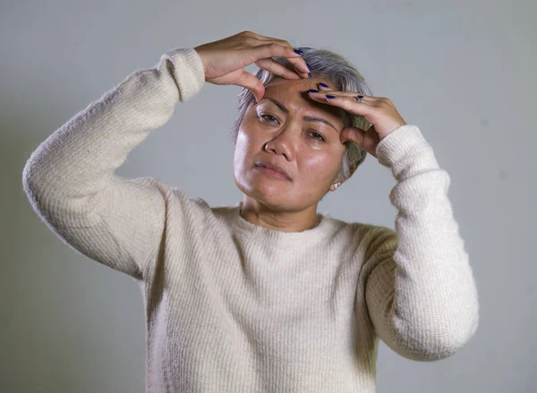 Dramatisches Porträt einer attraktiven, traurigen und depressiven asiatischen Frau mittleren Alters, die hilflos weint und unter Depressionen leidet. — Stockfoto