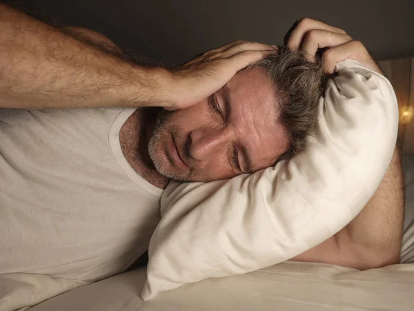 절망적이고 우울한 중년 남자는 침대에서 압도되고 좌절된 불안 위기와 우울증을 겪고 잠을 잘 수 없습니다. — 스톡 사진