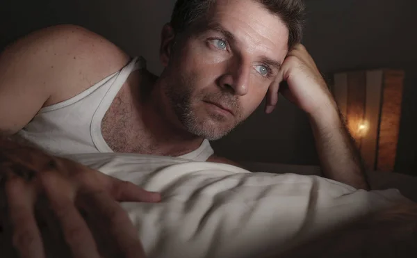 Close up face portrait of attractive sad and thoughtful man lying on bed awake late at night thinking feeling worried and concerned after divorce — Stock Photo, Image